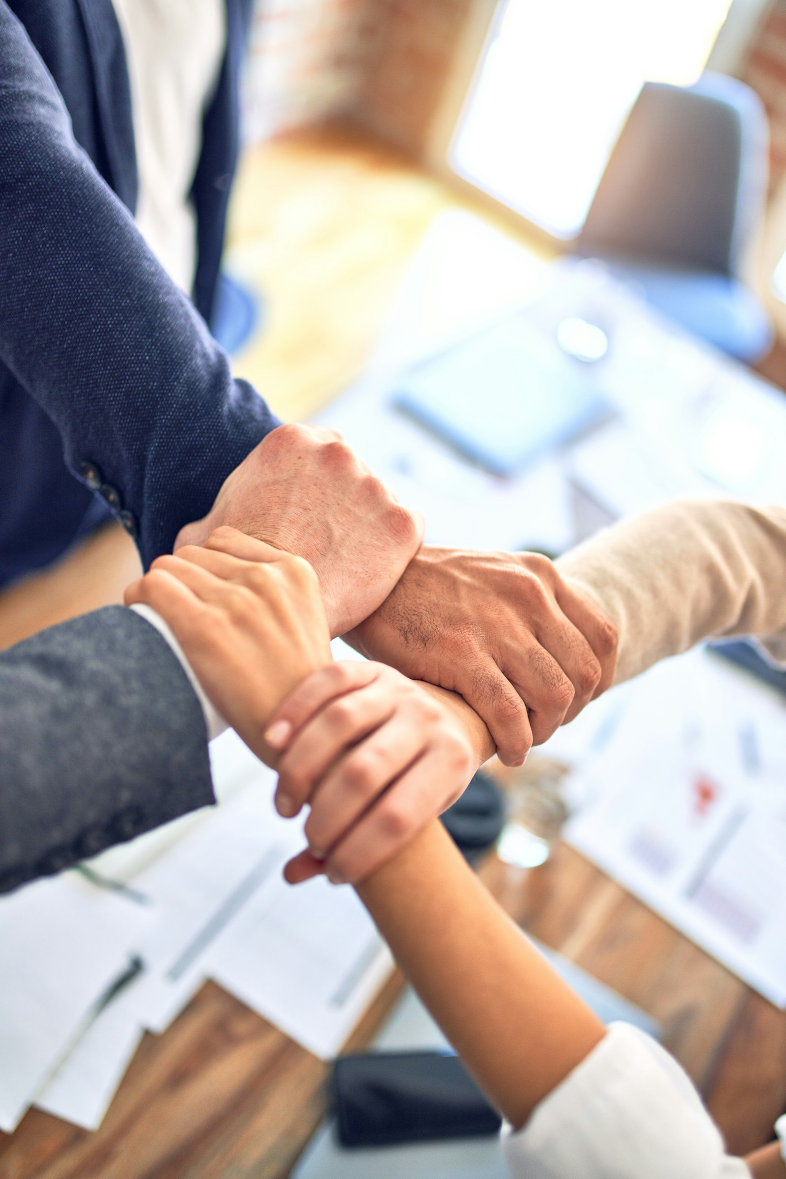 A team of certified practitioners joining hands in commitment over a project plan